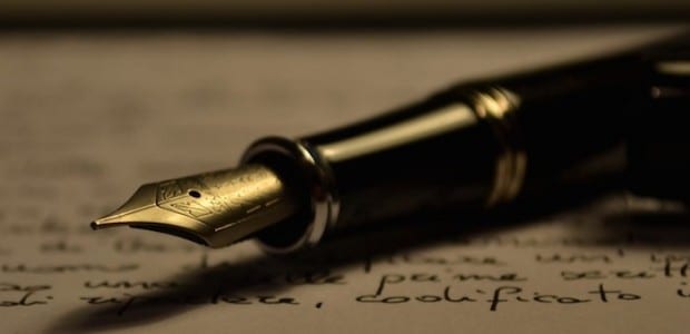 Bilden visar en gammaldags penna mot ett papper
